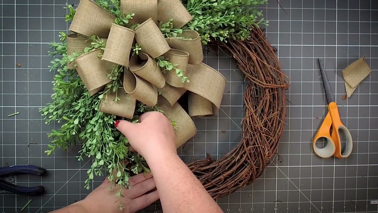Step 10: Tuck Greenery Through the Bow and Drop the Tails - How to Make a Wreath